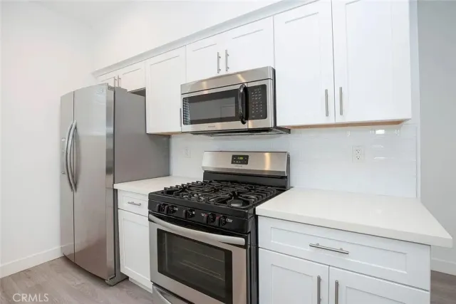 a kitchen with stainless steel appliances granite countertop white cabinets a stove a microwave and a refrigerator