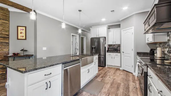 a modern kitchen with stainless steel appliances granite countertop a sink refrigerator and cabinets