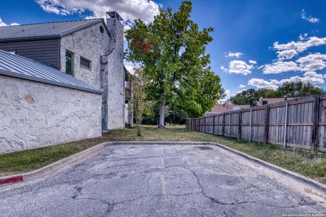 a view of backyard with potted plants and wooden fence