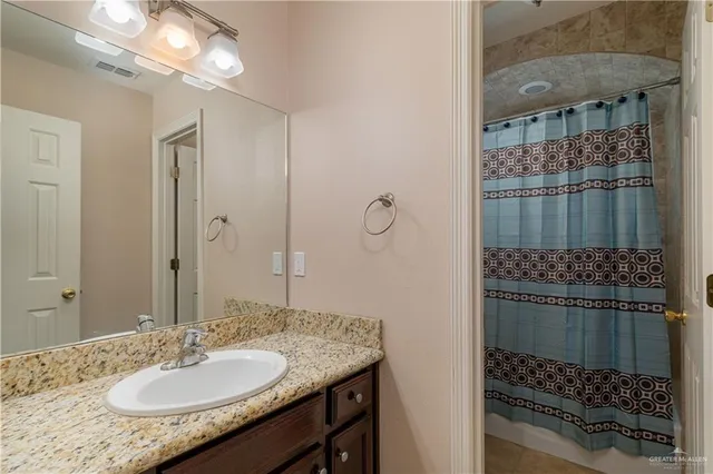 a bathroom with a sink vanity granite and shower