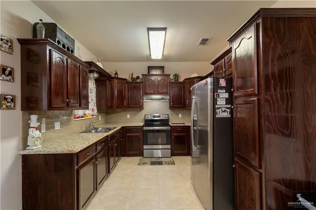 a kitchen with granite countertop a refrigerator stove and sink