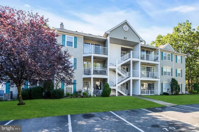 a view of a brick building next to a yard with big trees