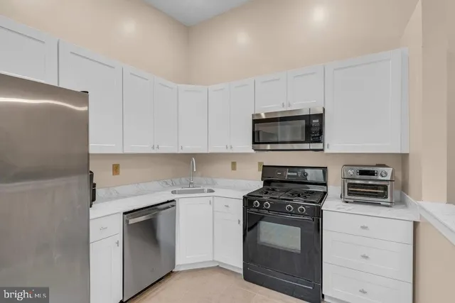 a kitchen with white cabinets and stainless steel appliances