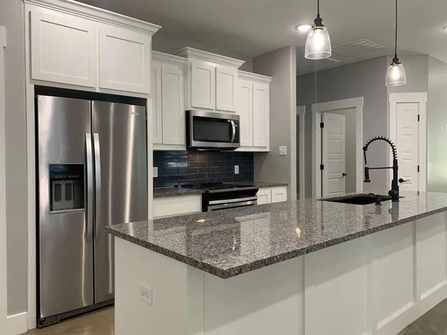 a kitchen with granite countertop a refrigerator and a sink