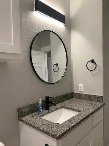 a bathroom with a granite countertop sink and mirror