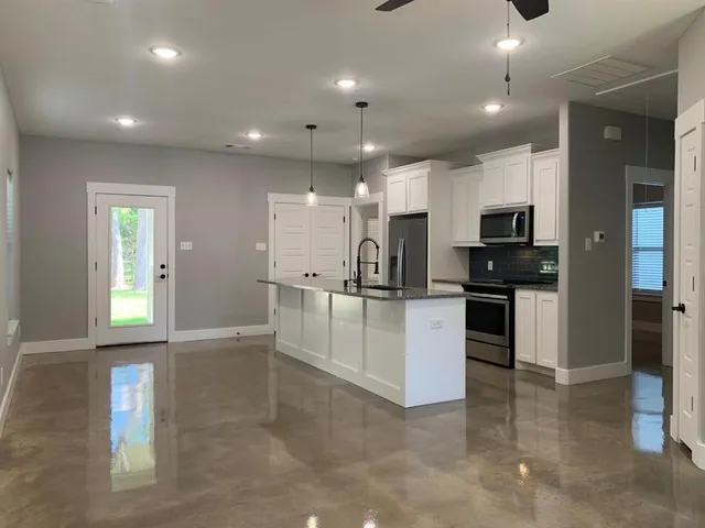 a view of kitchen with kitchen island white cabinets and stainless steel appliances
