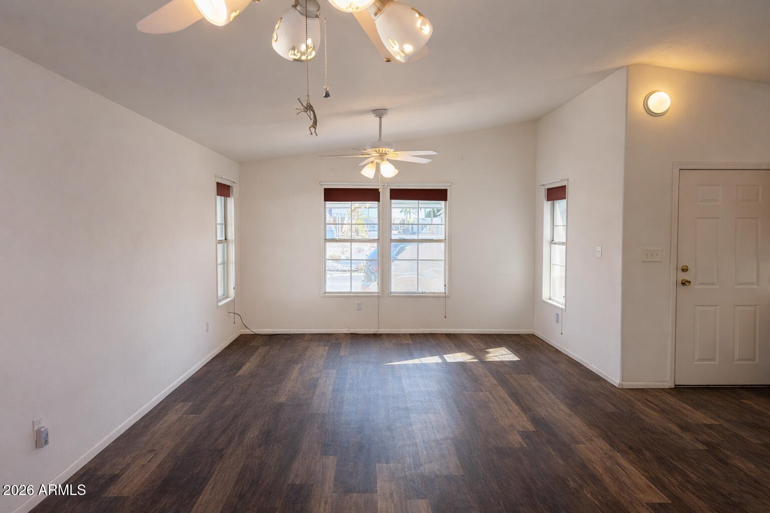 3700 South Tomahawk Road, Unit 13 Apache Junction, AZ 85119 - Photo 11 of 19 an empty room with wooden floor chandelier fan and windows