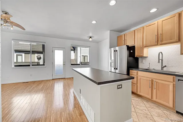 a kitchen with stainless steel appliances granite countertop a refrigerator a sink dishwasher a stove with wooden cabinets and floors