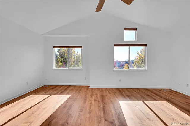 a view of an empty room with a window and wooden floor