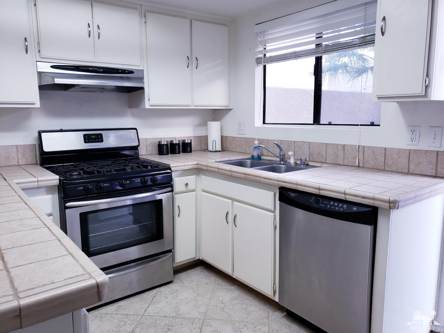 69575 Karen Way Rancho Mirage, CA 92270 - Photo 5 of 14 a kitchen with granite countertop white cabinets and white appliances