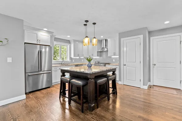 a kitchen with a refrigerator a sink dishwasher a dining table and chairs with wooden floor