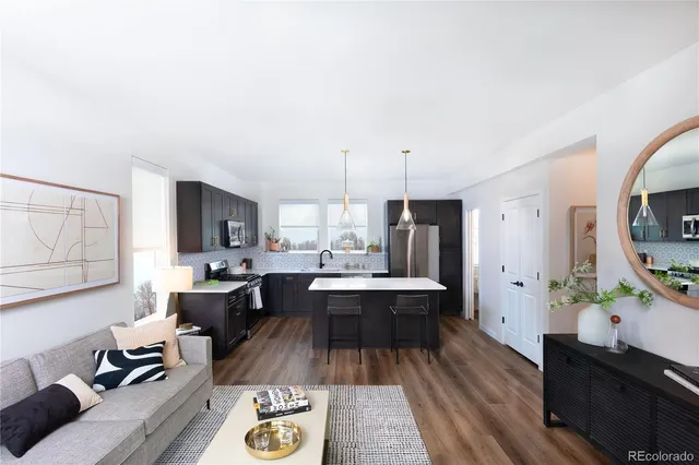 a view of living room kitchen with stainless steel appliances granite countertop furniture and a flat screen tv
