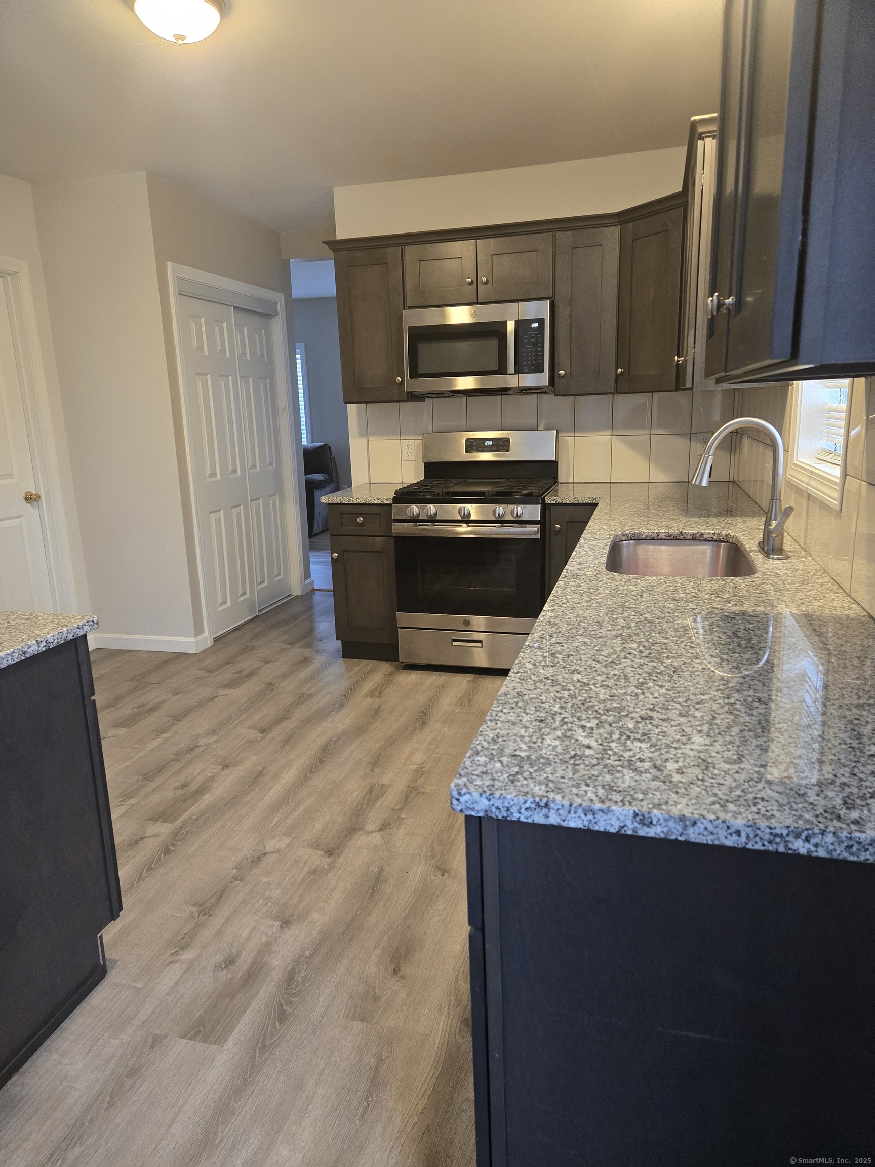 112 Liberty Street Pawcatuck, CT 06379 - Photo 4 of 22 a kitchen with kitchen island granite countertop a sink dishwasher stove and refrigerator with wooden floor