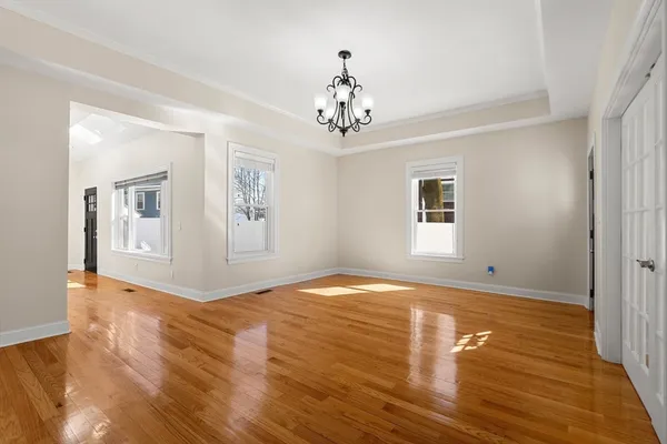 a view of an empty room with window and wooden floor