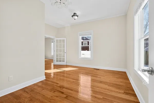 a view of an empty room with wooden floor and a window