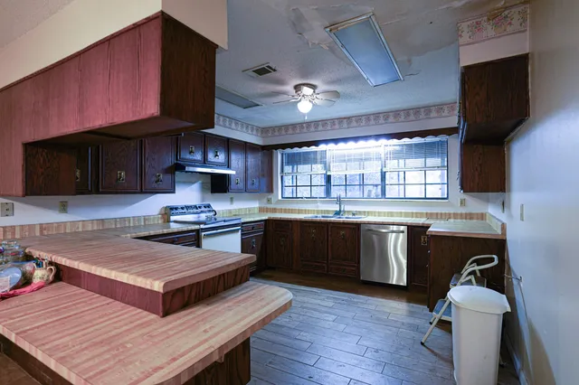 a kitchen with stainless steel appliances granite countertop wooden cabinets and a sink