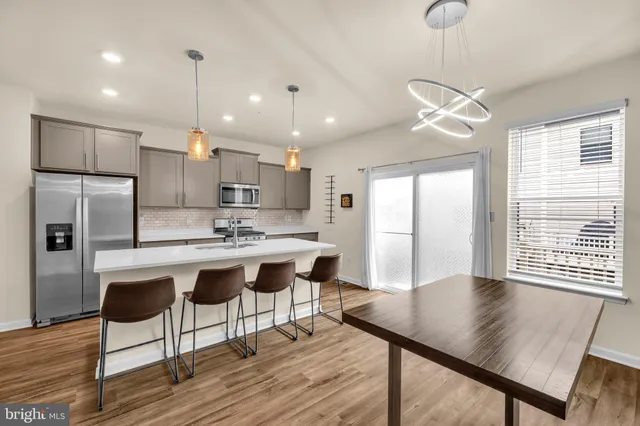 a kitchen with stainless steel appliances granite countertop a sink a stove a refrigerator and white cabinets with wooden floor