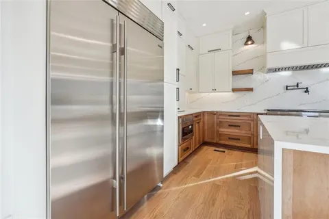 a view of a kitchen with stainless steel appliances granite countertop a lot of cabinets and wooden floor