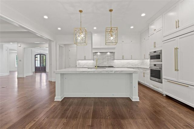 a large kitchen with stainless steel appliances kitchen island granite countertop a large counter top and a stove top oven