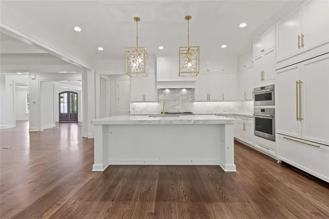 a large kitchen with stainless steel appliances kitchen island granite countertop a large counter top and a stove top oven