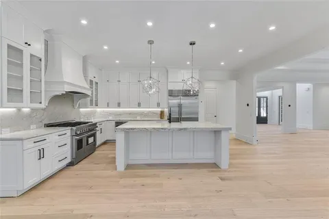 a kitchen with stainless steel appliances granite countertop a sink a stove and a wooden floors