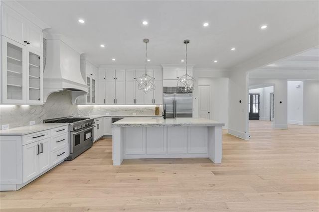 a kitchen with stainless steel appliances granite countertop a sink a stove and a wooden floors