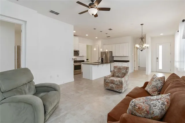 a living room with furniture kitchen view and a chandelier