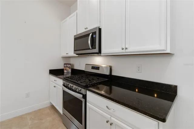 a kitchen with granite countertop white cabinets and black appliances