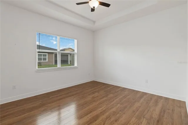 a view of empty room with wooden floor and chandelier fan