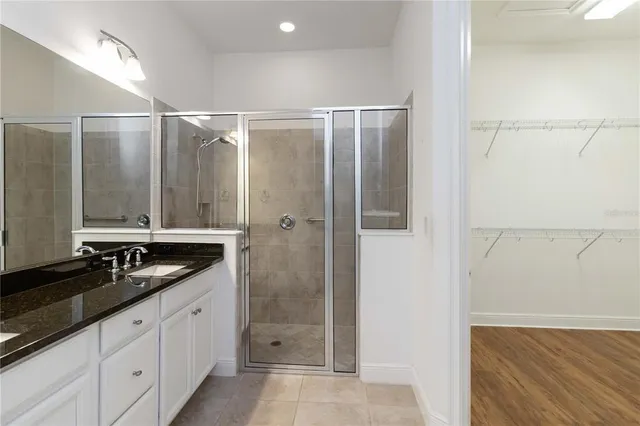 a bathroom with a granite countertop sink a mirror and a shower