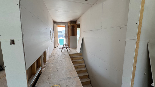 1862 Mantle Way, Unit 418 Tooele, UT 84074 - Photo 5 of 10 Interior hallway showcasing new drywall installation and a partially constructed wooden staircase, featuring exposed framing and a visible exterior door