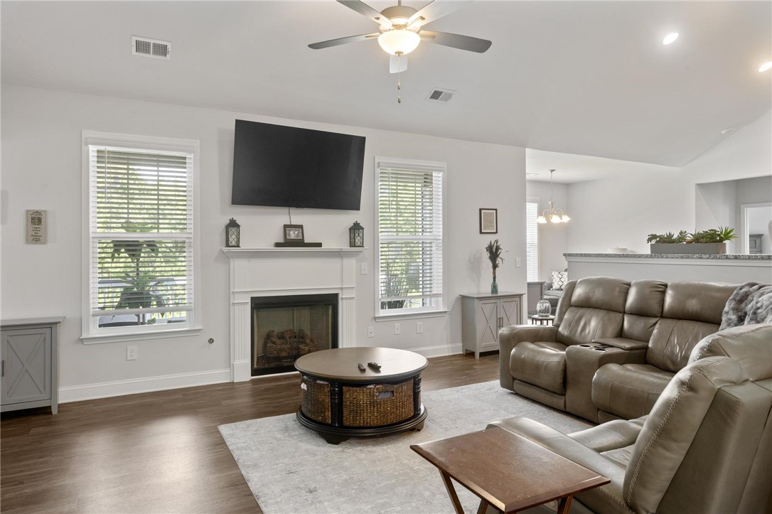 125 Estateside Drive Anderson, SC 29621 - Photo 12 of 37 A well-lit living area features rich hardwood flooring, a cozy fireplace, and an inviting atmosphere.