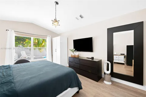 a bedroom with a bed and a flat tv screen on dresser