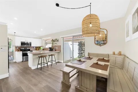 a kitchen with stainless steel appliances kitchen island granite countertop a stove top oven a sink a dining table and chairs with wooden floor