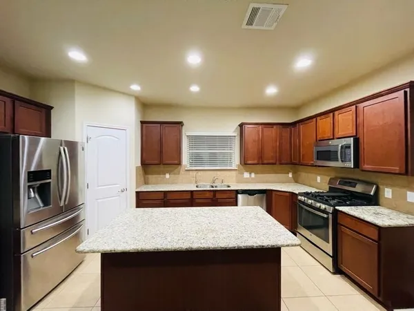 a kitchen with granite countertop wooden cabinets and stainless steel appliances