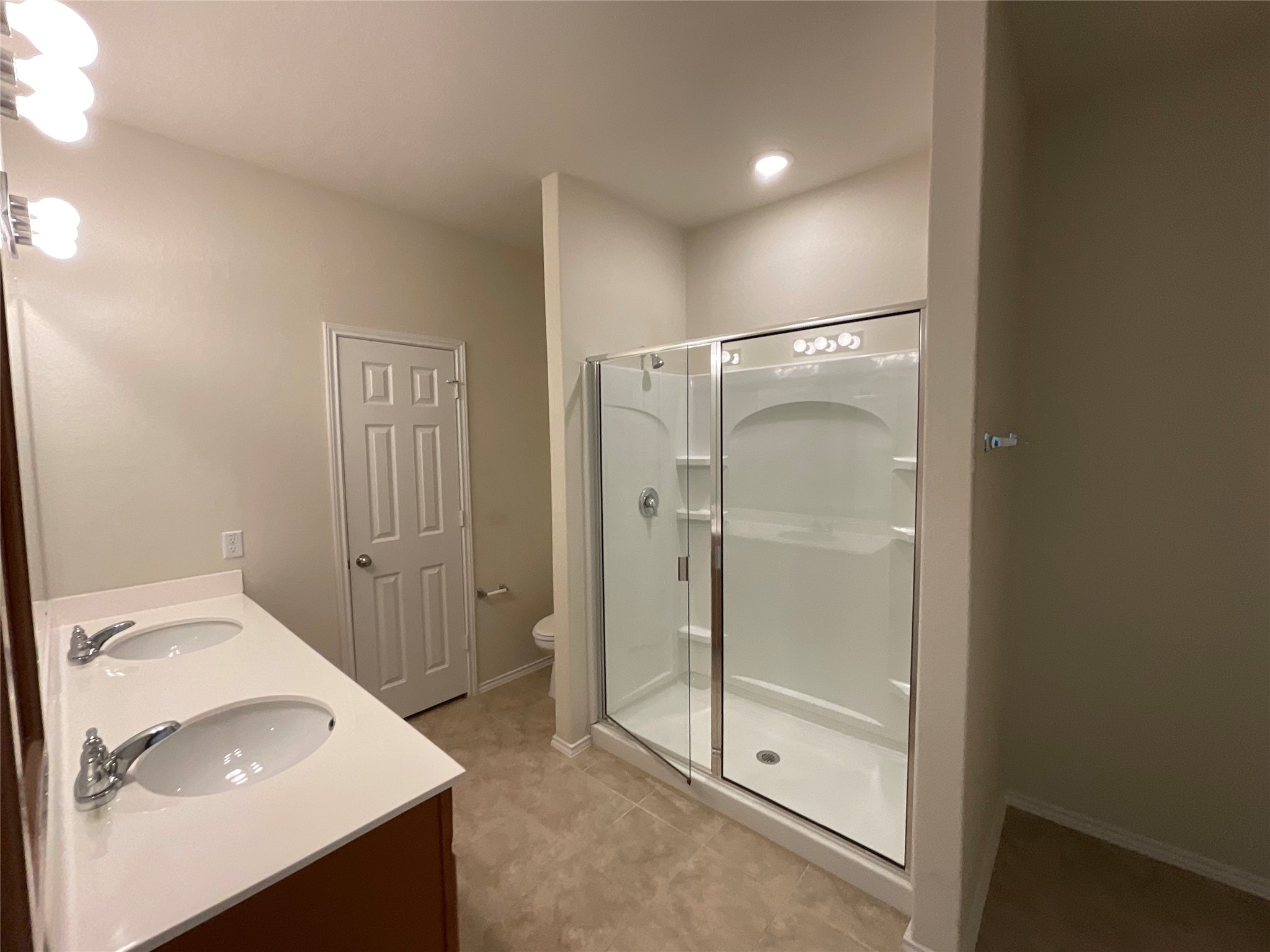 3451 Mayfield Ranch Boulevard, Unit 311 Round Rock, TX 78681 - Photo 15 of 29 Full bath with double vanity, a shower stall, recessed lighting, and light tile patterned floors