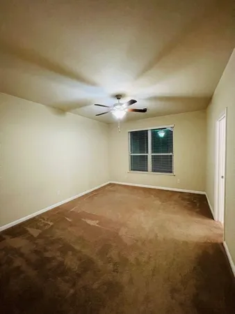 an empty room with a ceiling fan and window