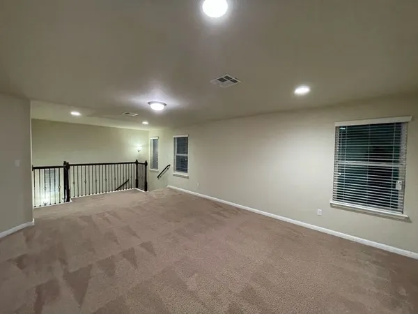 an empty room with a chandelier fan and windows