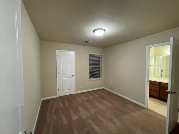 an empty room with a chandelier fan and windows