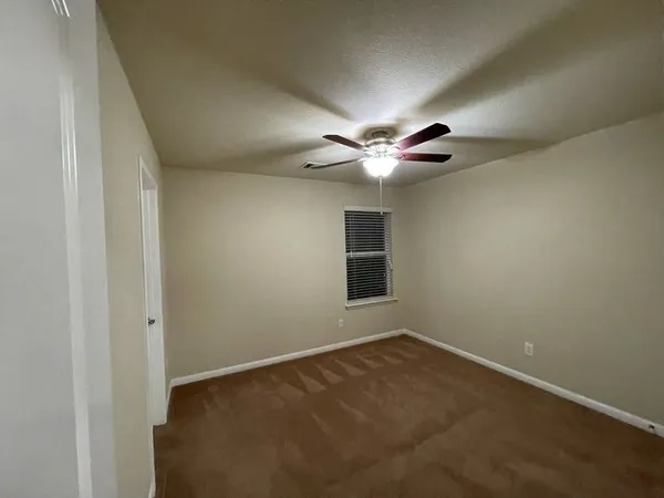 an empty room with closet and a ceiling fan