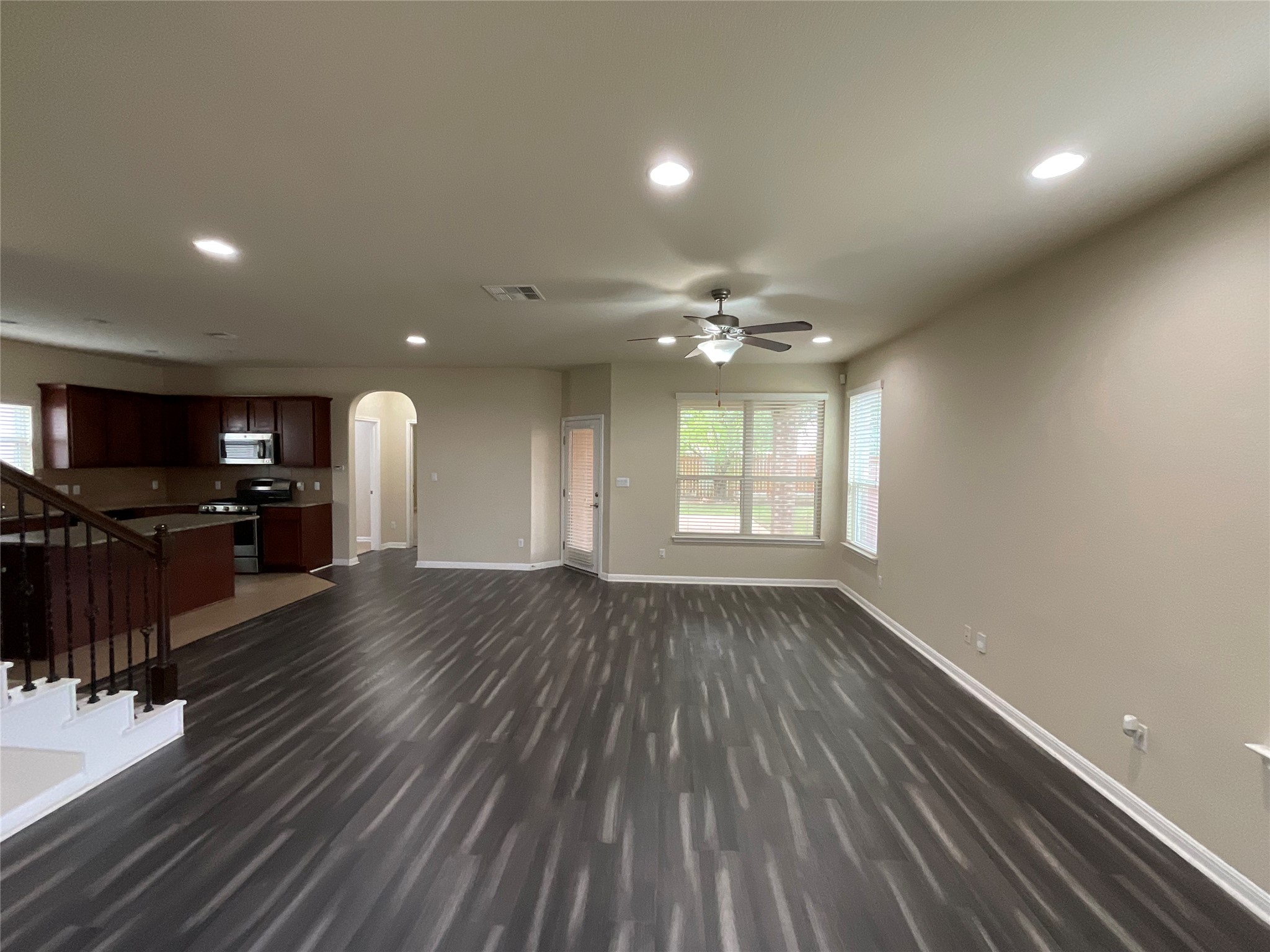 3451 Mayfield Ranch Boulevard, Unit 311 Round Rock, TX 78681 - Photo 5 of 29 Unfurnished living room featuring arched walkways, recessed lighting, ceiling fan, dark wood-style floors, and plenty of natural light