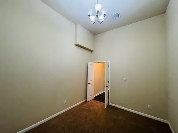 an empty room with a chandelier fan and wooden floor