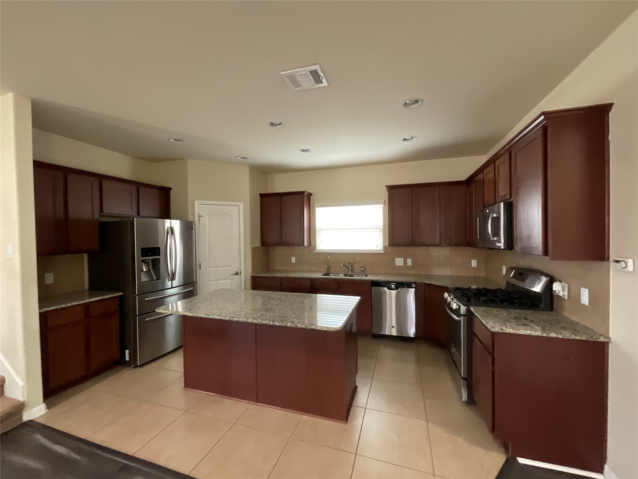 3451 Mayfield Ranch Boulevard, Unit 311 Round Rock, TX 78681 - Photo 9 of 29 Kitchen with stainless steel appliances, light stone counters, light tile patterned floors, a center island, and decorative backsplash