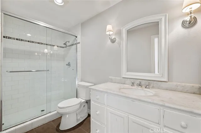 a bathroom with a granite countertop sink toilet a mirror and shower