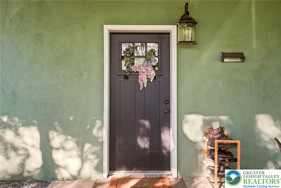 9033 Loop Road Slatington, PA 18080 - Photo 19 of 53 A welcoming entry featuring a dark door with an intricate glass panel, set against a light green wall.