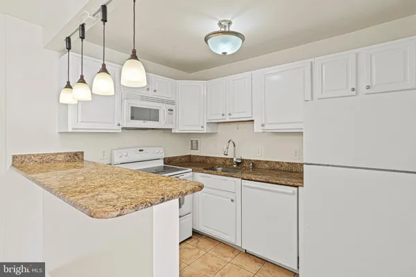a kitchen with granite countertop a sink a stove and cabinets