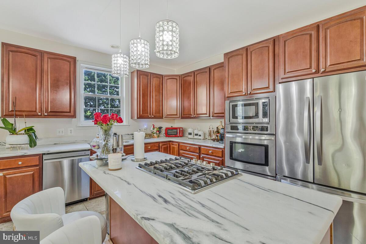 215 Hoile Lane Huntingtown, MD 20639 - Photo 15 of 52 a kitchen with stainless steel appliances a stove a sink dishwasher a refrigerator cabinets and a dining table with wooden floor