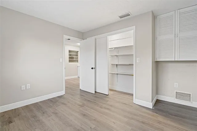 a view of an empty room with a closet and wooden floor