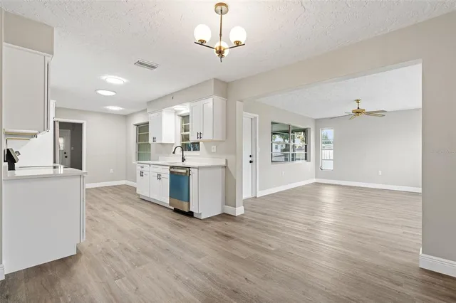 a large white kitchen with cabinets and wooden floor