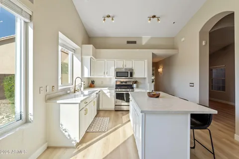 a kitchen with stainless steel appliances kitchen island a table chairs sink and cabinets